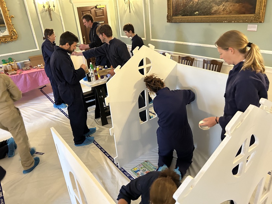 A team painting wooden playhouses for a children’s charity